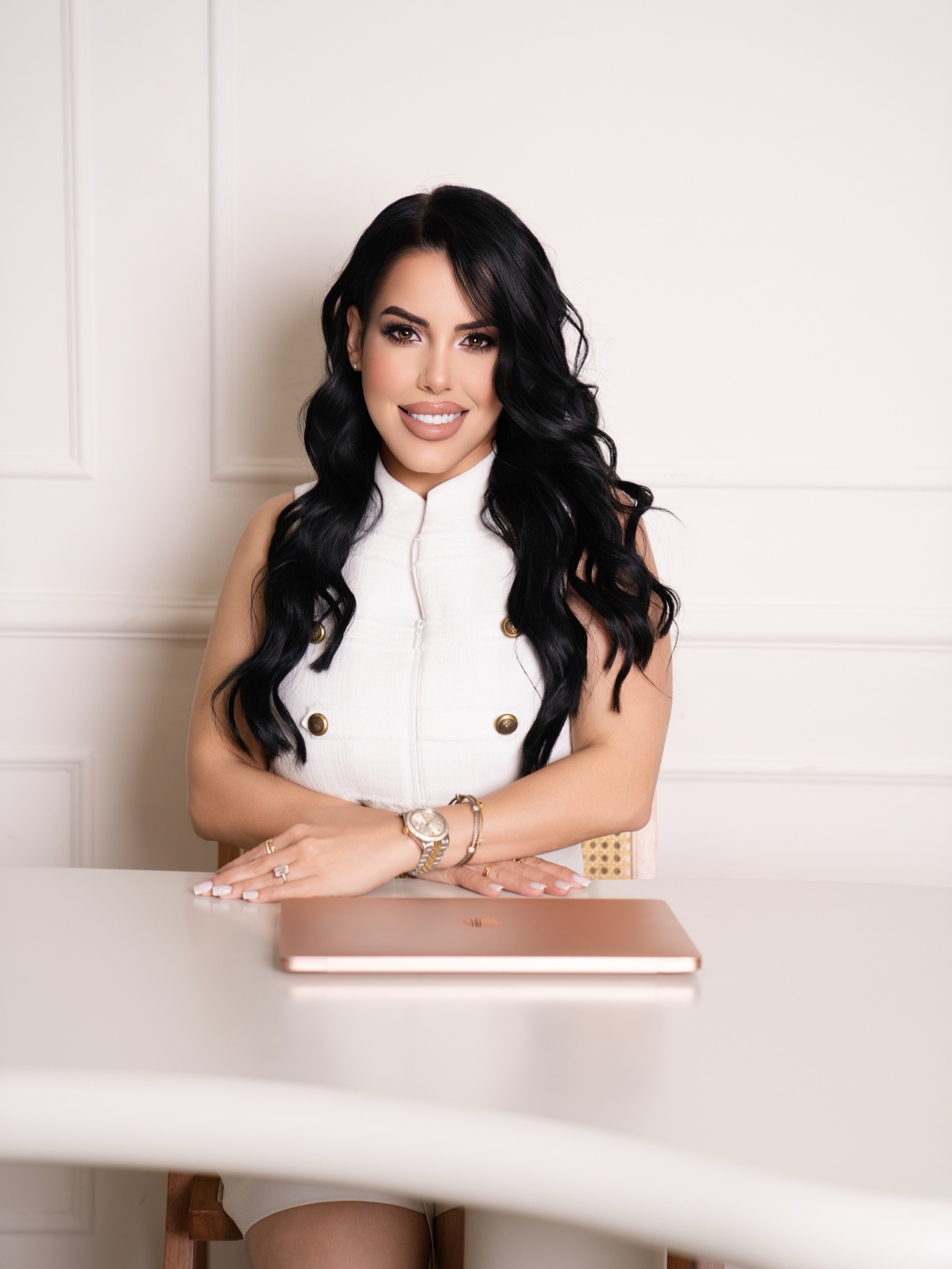 Broker Neily Cabrera seated at a desk in a white outfit